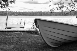 A boat set aground, against a lake, all in black and white.