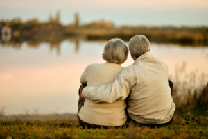 Couple cuddling with a lakeside view.