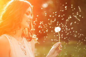 Person Blowing daisies into the wind.