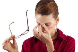 Person taking off their glasses and pinching the bridge of their nose.