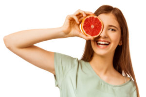 Person holding a grapefruit over their eye.